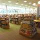 1Ｆの｢こども図書館｣。屋外には田園風景が広がっている。奥には｢キッズルーム｣と｢おはなしのへや｣があり、大型絵本などを配架している